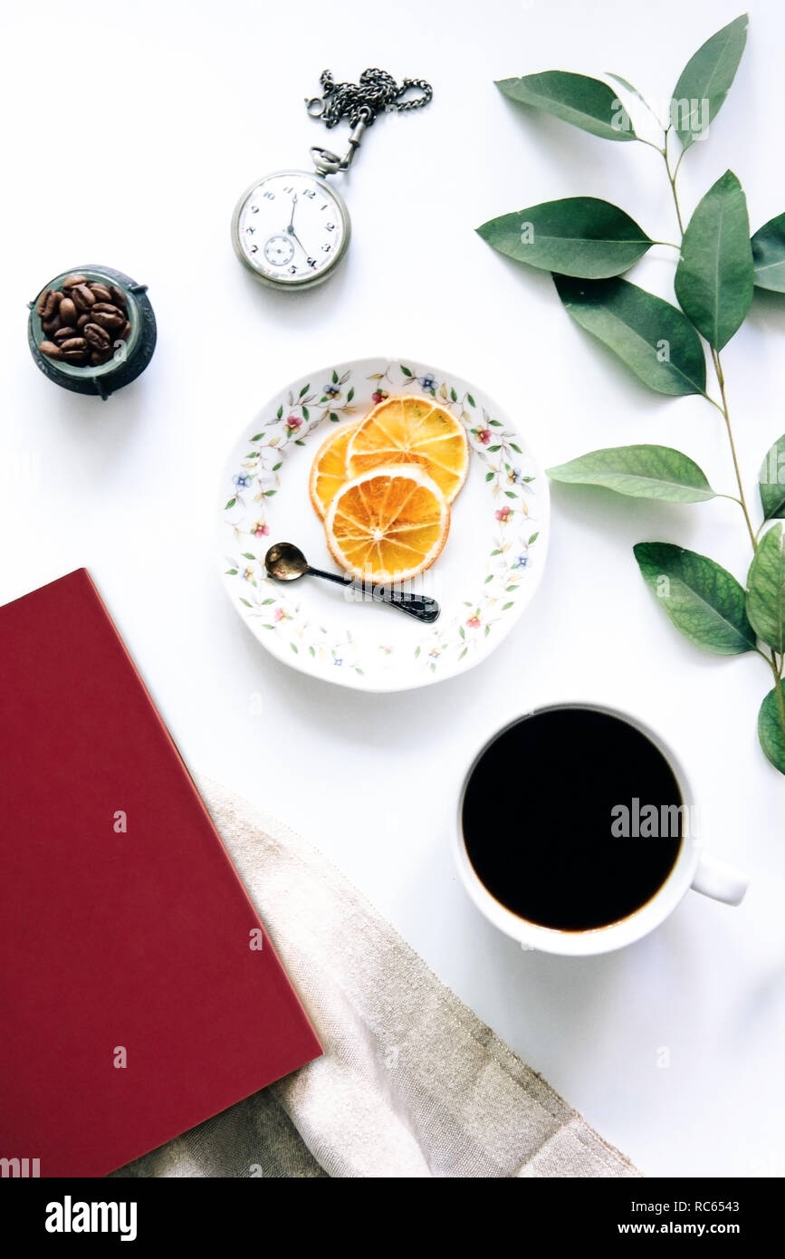 Il caffè e il libro rosso sul tavolo con secchi Arance e il vecchio orologio da tasca - Ambiente tranquillo - Tea time - Ambiente di lavoro Foto Stock