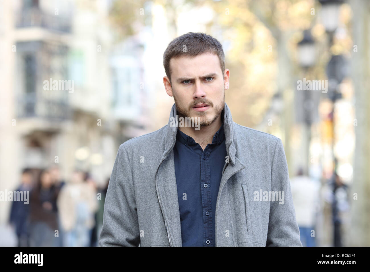Vista frontale ritratto di un uomo arrabbiato a piedi in strada guardando la fotocamera Foto Stock