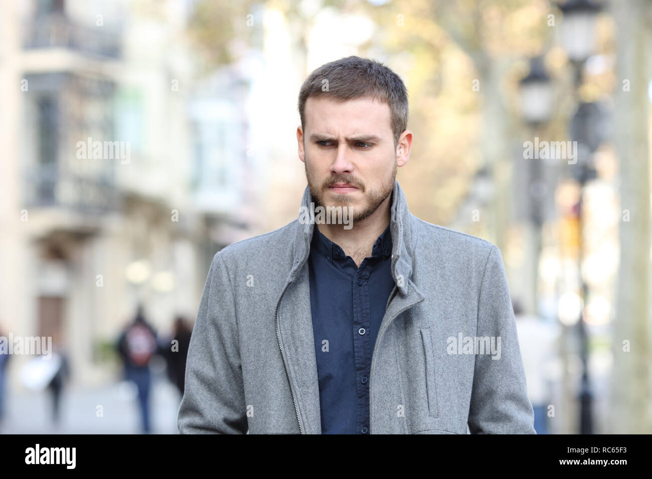 Vista frontale di un arrabbiato uomo a camminare verso la telecamera in strada Foto Stock