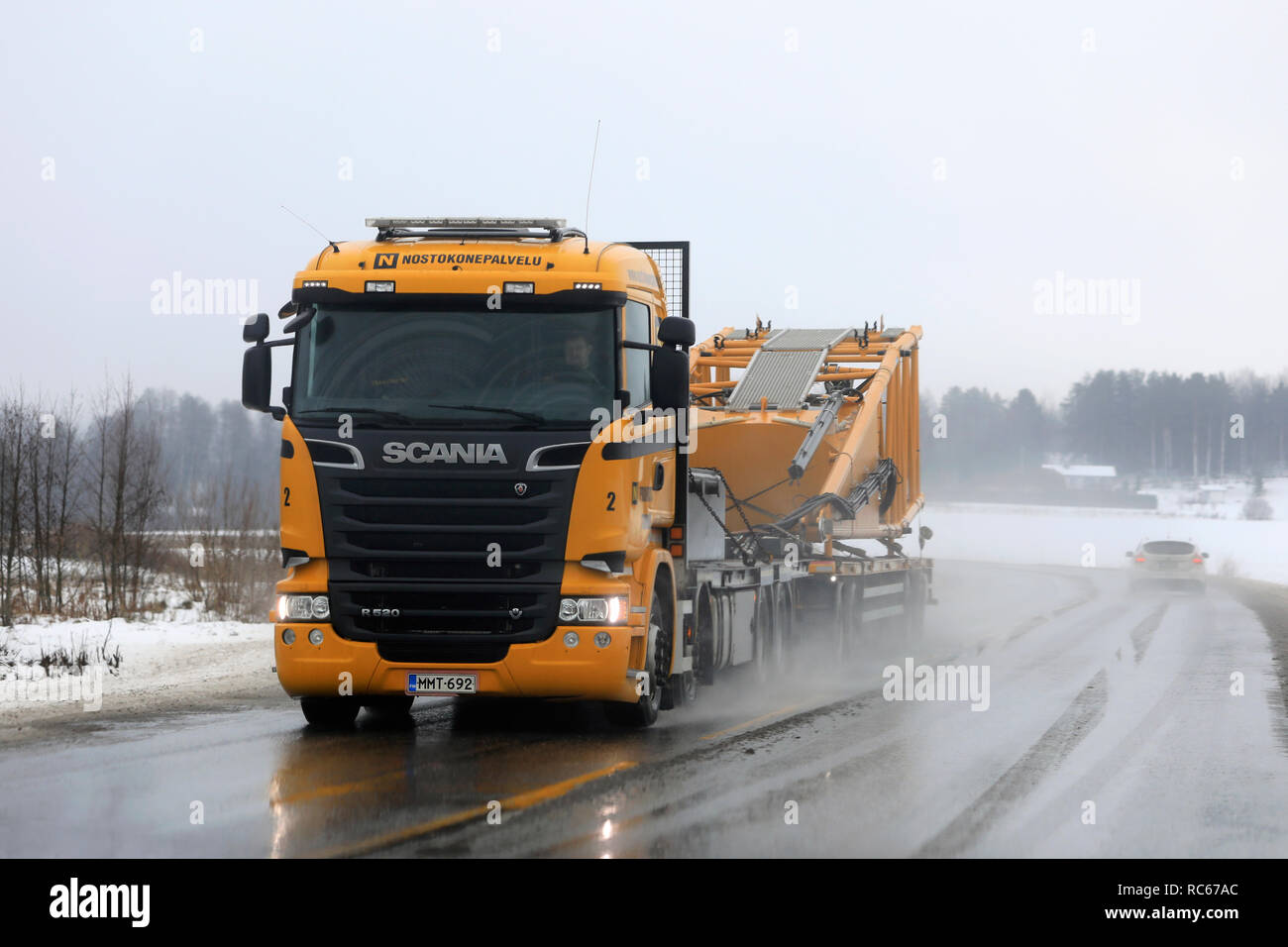 Salo, Finlandia - 4 Gennaio 2019: Giallo Scania R520 semi rimorchio di Nostokonepalvelu cale di apparecchiature di sollevamento su de-autostrada ghiacciata su un nebbioso giorno di wint Foto Stock