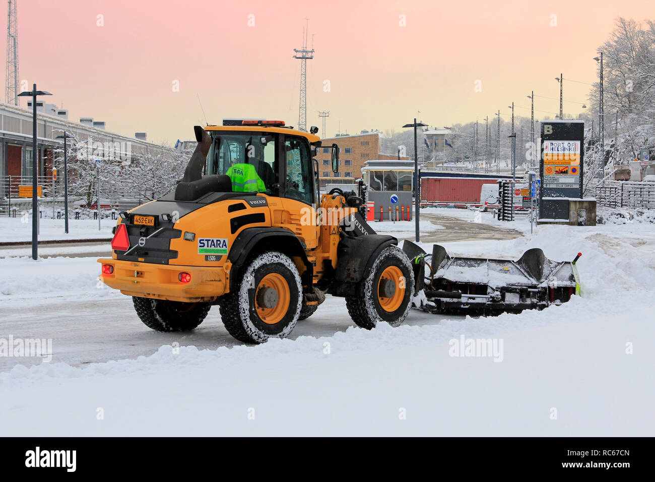 Helsinki, Finlandia - 9 Gennaio 2019: rimozione della neve con Volvo L50G pala caricatrice gommata compatta dotata di spartineve vicino al porto di Helsinki il giorno dell'inverno. Foto Stock