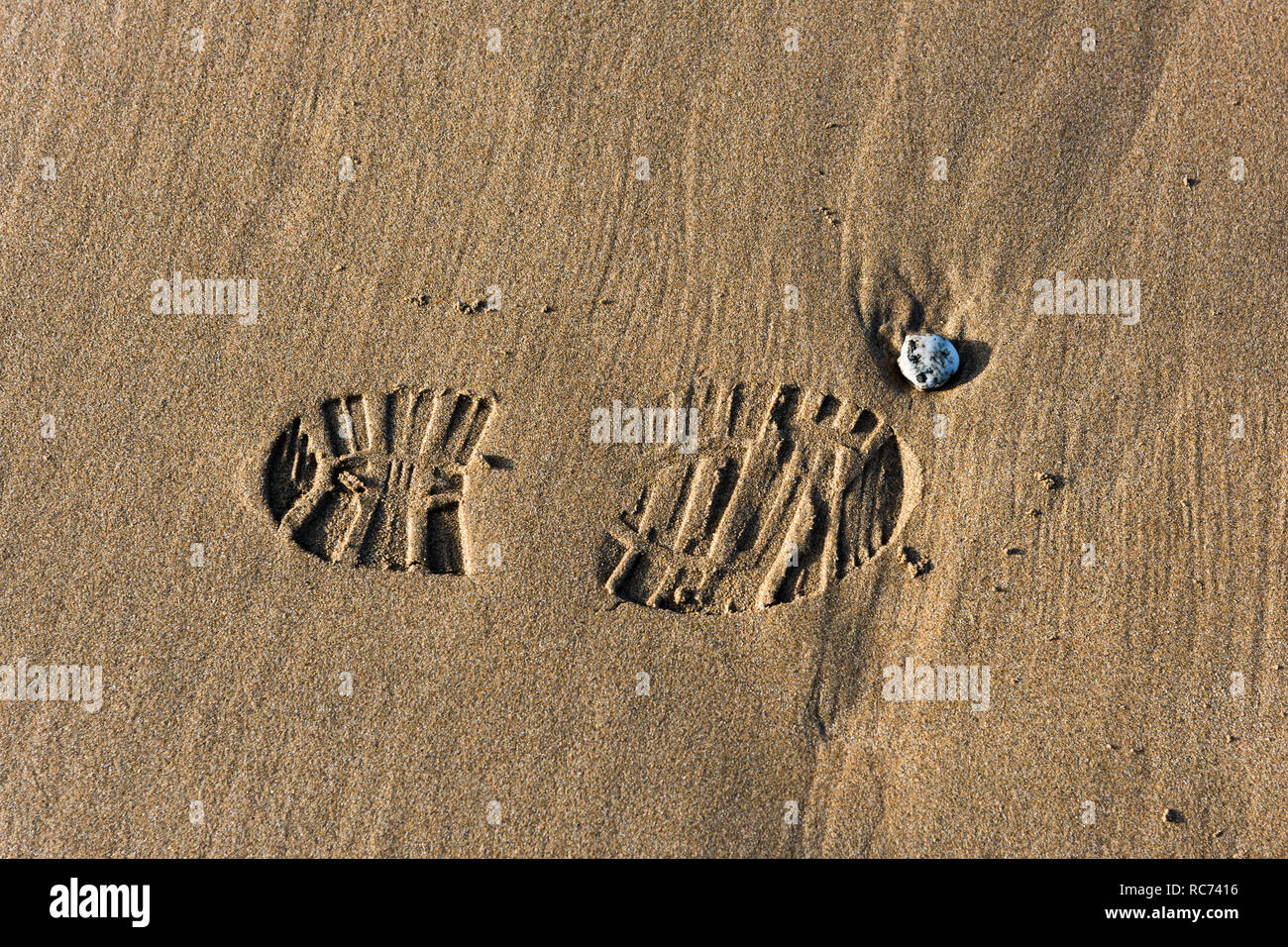 Una sola impronta di un shoeprint in sabbia bagnata su una spiaggia. Foto Stock