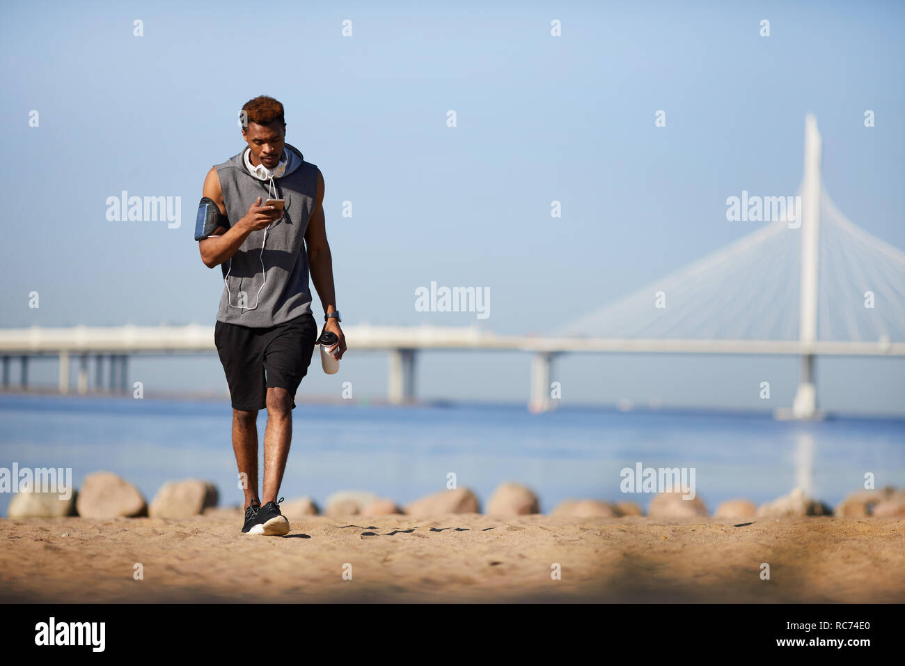 Grave ragazzo nero scrivere messaggi SMS mentre passeggiate sulla spiaggia Foto Stock Grave ragazzo nero scrivere messaggi SMS mentre passeggiate sulla spiaggia Foto Stock