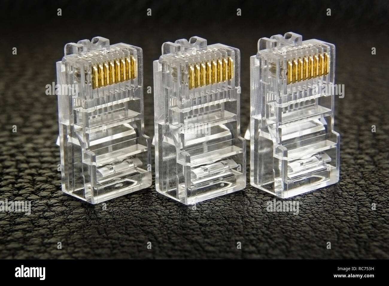 Tre connettori RJ-45 in una fila di close-up su sfondo scuro Foto Stock