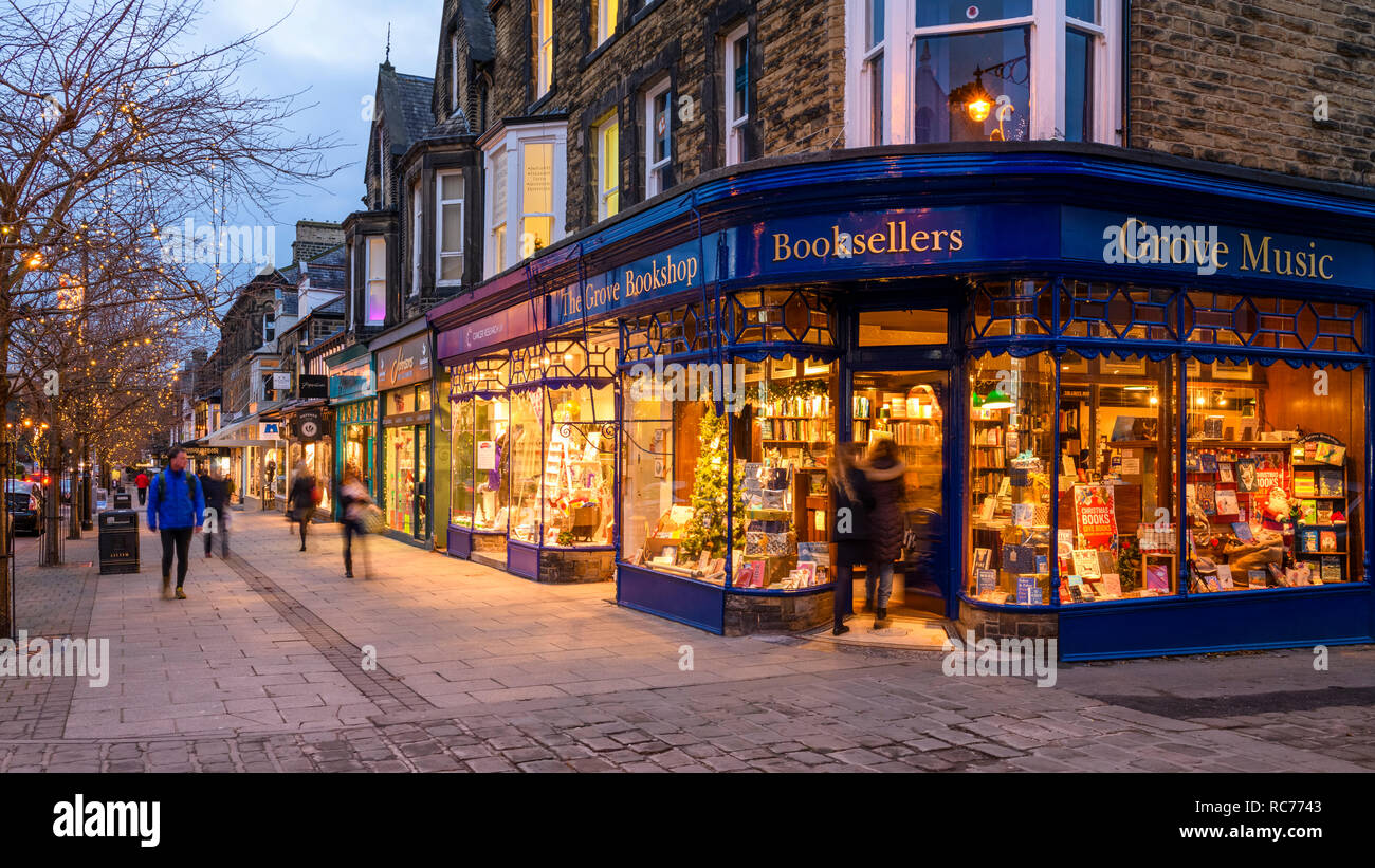 Bagliore dorato di luci & attraente vetrina esterno del Grove Bookshop è accogliente come la gente a piedi o in passato - Ilkley, West Yorkshire, Regno Unito. Foto Stock