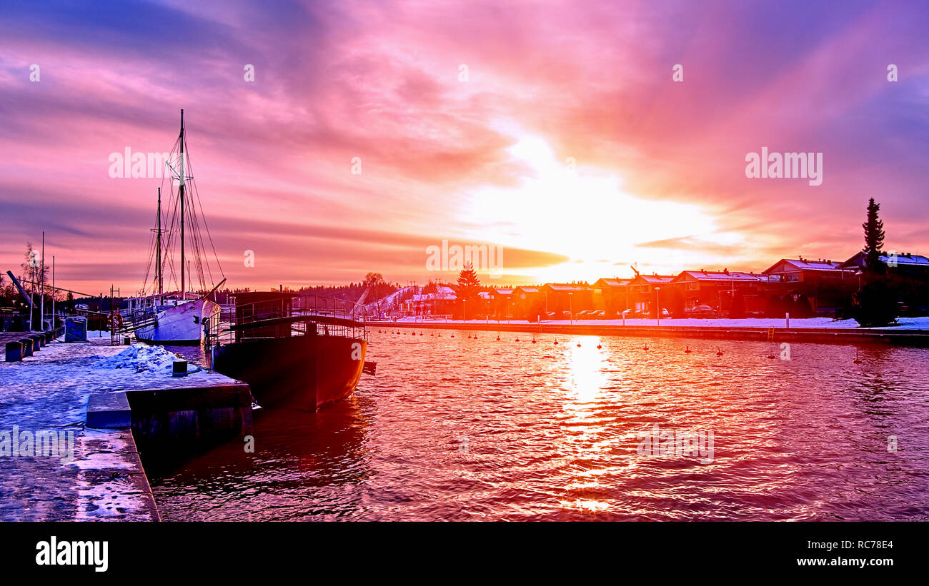 New Scenic 5 posti rosso porpora e viola tramonto sul fiume di campagna in Europa con le vecchie navi aventi il resto al porto nevoso pier Foto Stock