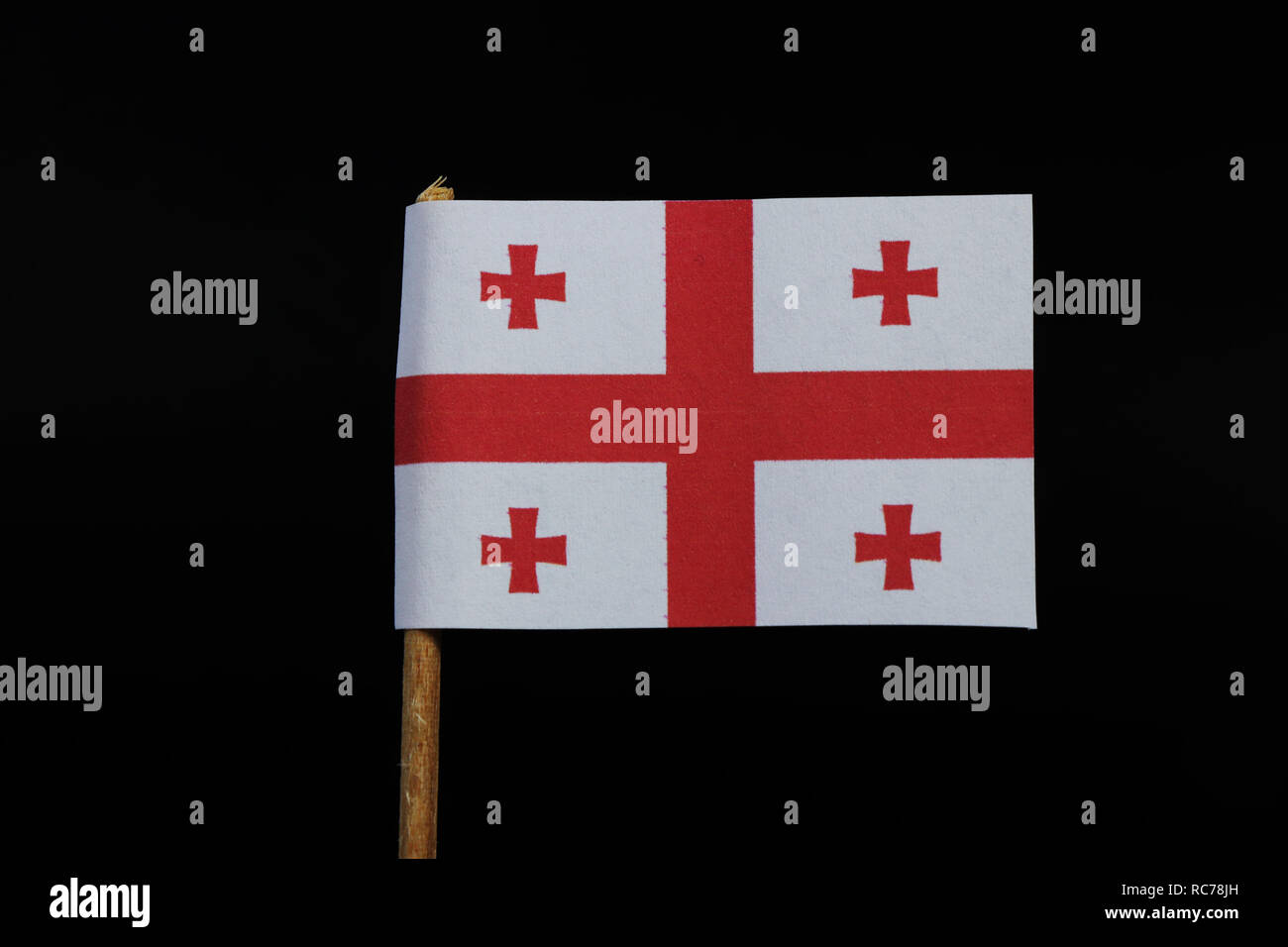 Una bandiera nazionale della Georgia su stuzzicadenti su sfondo nero. Un campo  bianco con una posizione centrata di croce rossa al centro di ciascun  trimestre è un rosso Bolnur-Kat Foto stock -