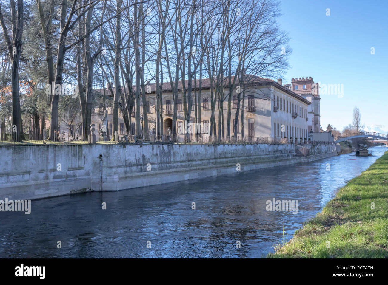 Vista della antica villa e la sua patk con enormi alberi sul terrapieno artificiale della storica canal, girato in inverno una luce brillante a Robecco sul Naviglio, Mi Foto Stock