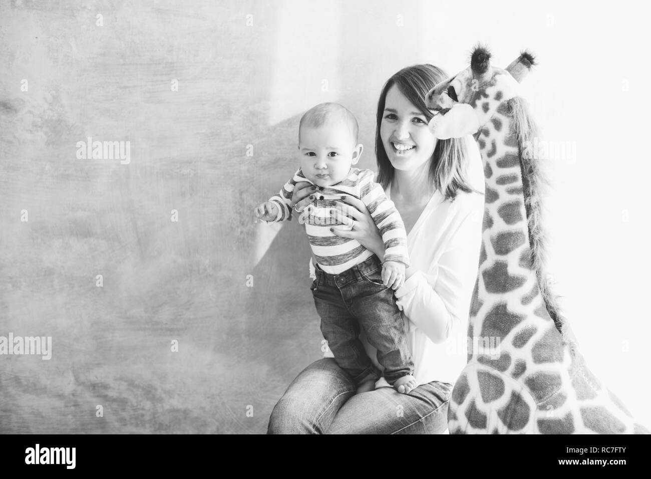 Azienda madre baby boy accanto a giraffa giocattolo Foto Stock
