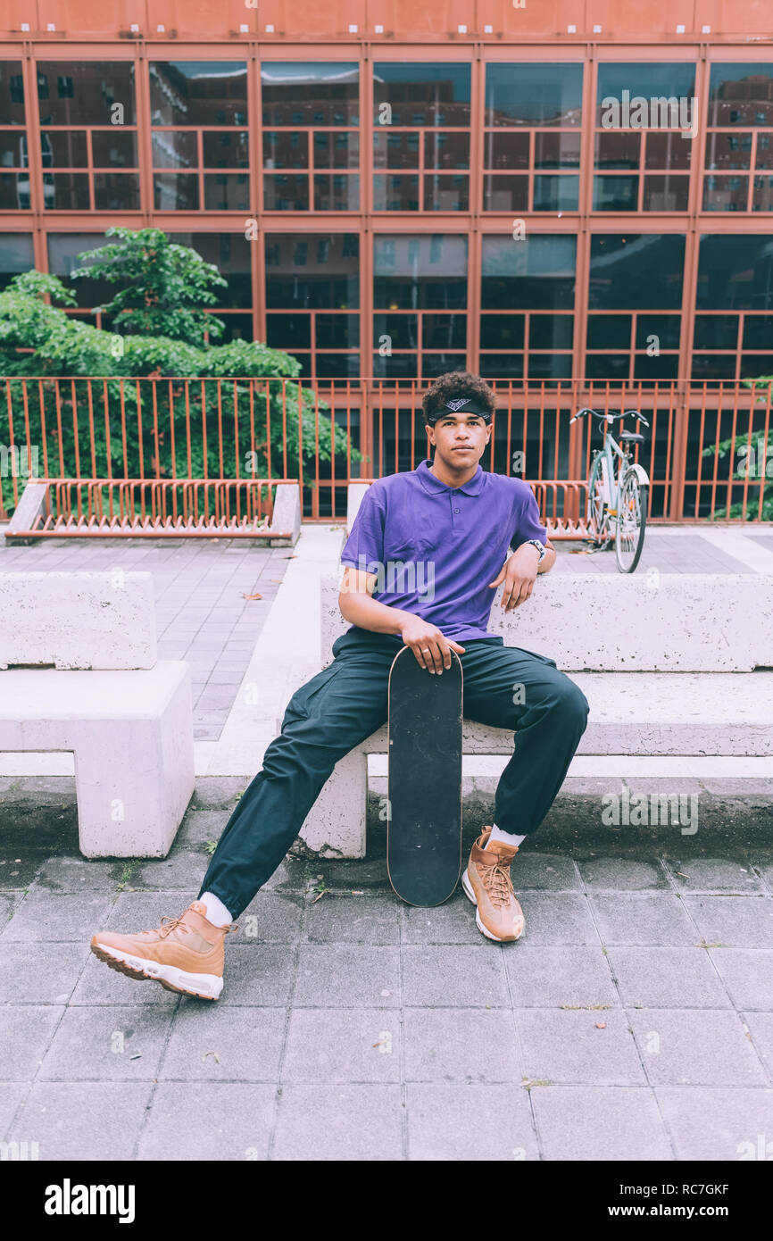 Guidatore di skateboard in posa con lo skateboard, Milano, Italia Foto Stock