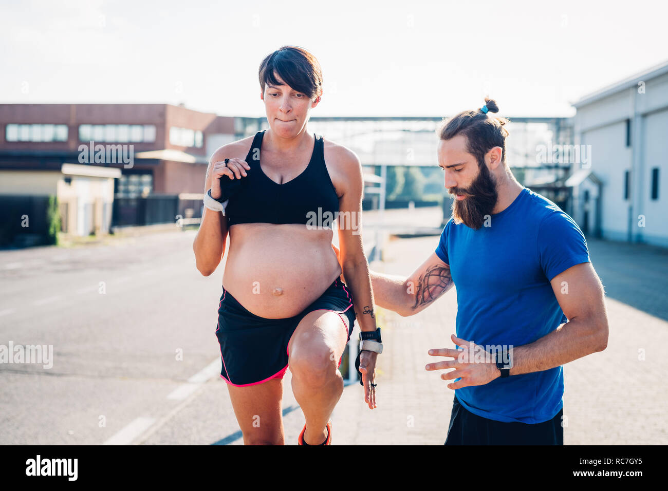 Donna incinta e personal trainer lavora fuori all'aperto Foto Stock