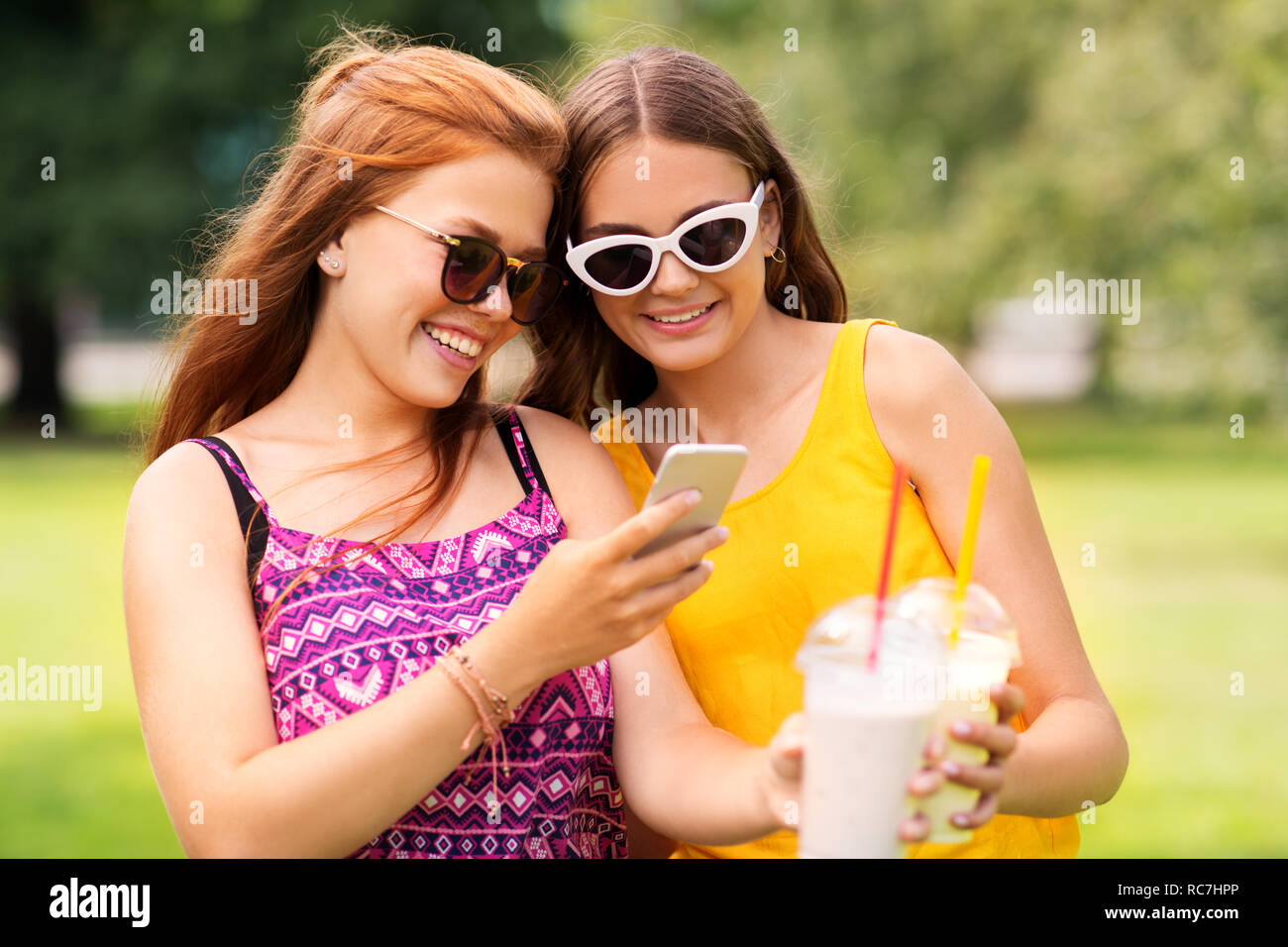 Le ragazze adolescenti con lo smartphone e scuote in posizione di parcheggio Foto Stock