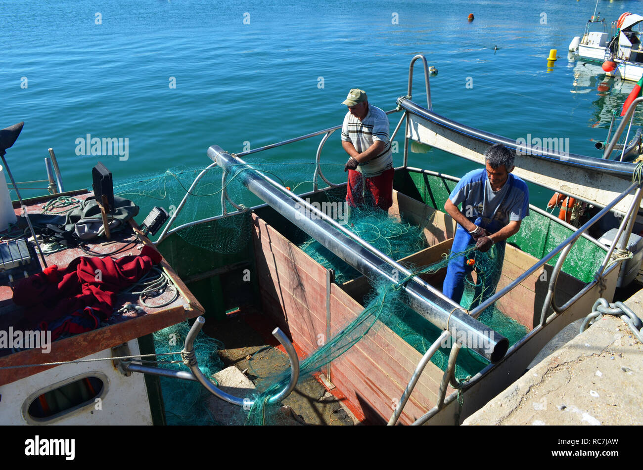 Pescatori che lavorano a bordo di un gillnetter artigianale nel porto di Lagos, Algarve, PORTOGALLO Foto Stock