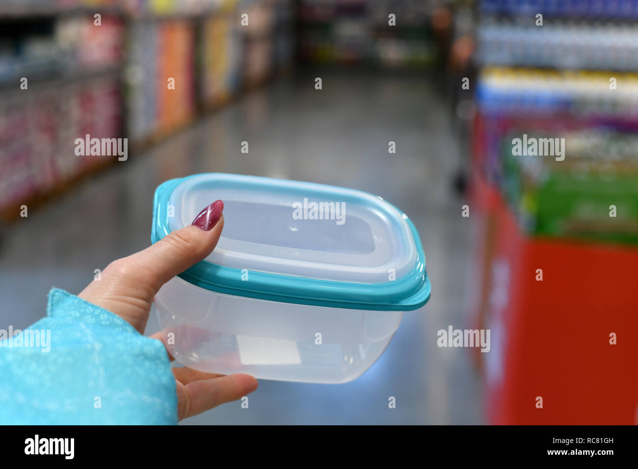 Contenitore in plastica per alimenti in mano femmina su sfondo shop Foto Stock