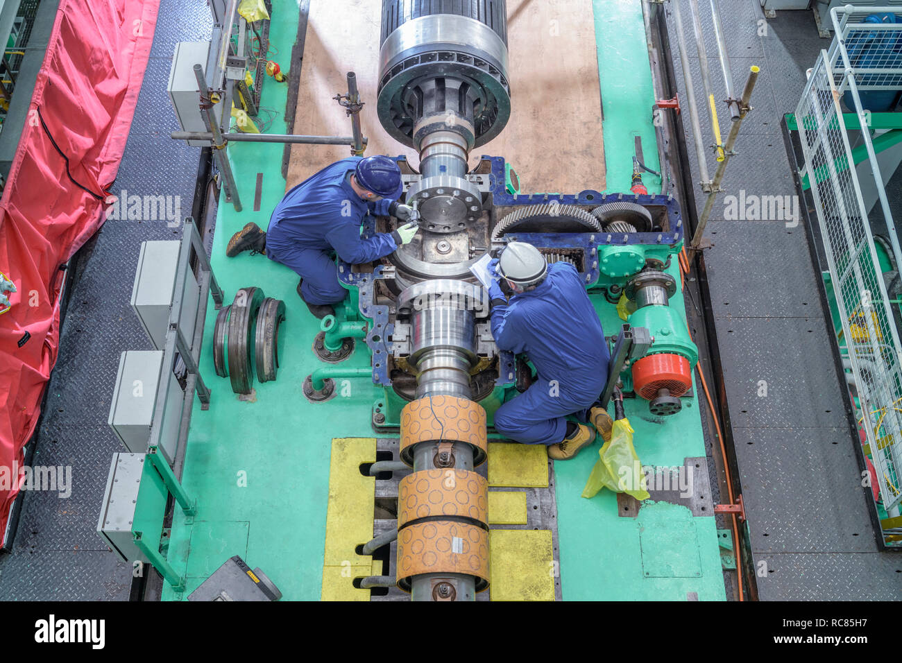 Vista aerea di ingegneri di ispezionare ingranaggi sul generatore nella sala della turbina della centrale nucleare in caso di interruzioni Foto Stock