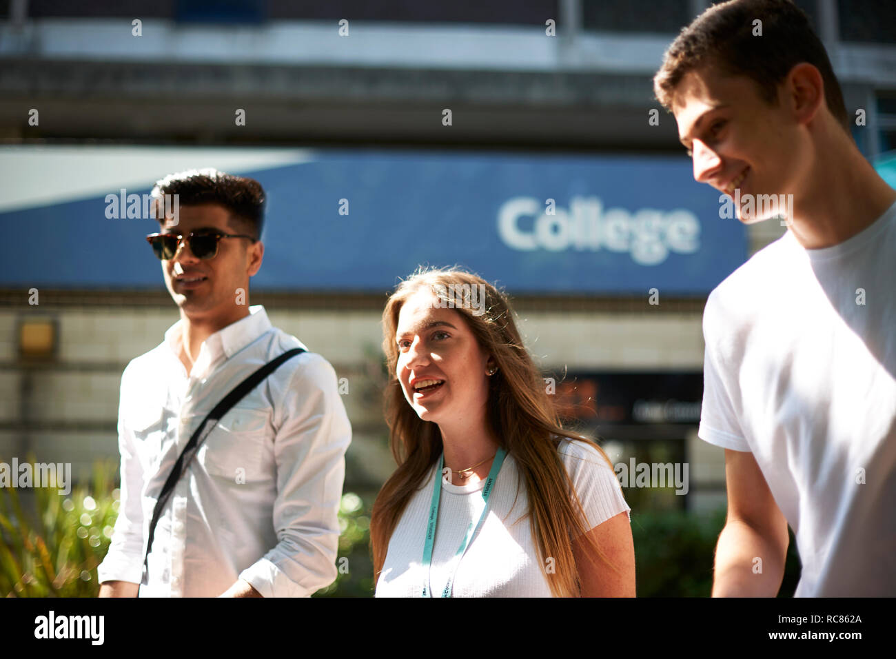 Ragazza adolescente con maschi giovani studenti universitari lasciando college campus Foto Stock