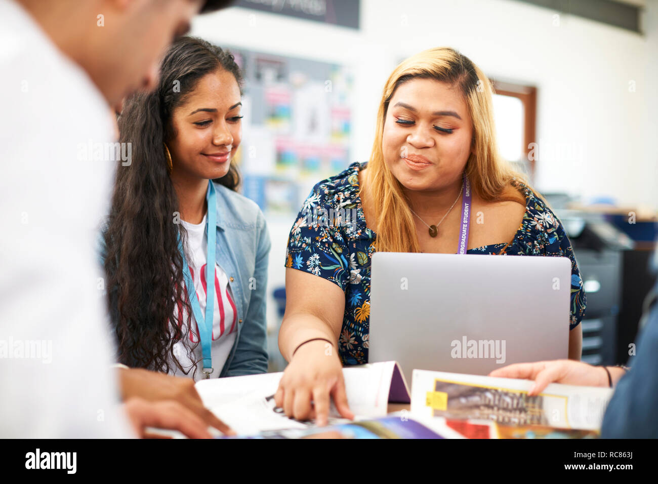 Maschi e femmine di istruzione superiore agli studenti di lavorare in team e utilizzando laptop in college classroom Foto Stock