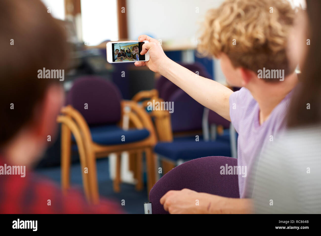 Maschio e femmina di istruzione superiore studenti prendendo selfie nel collegio di classe Foto Stock