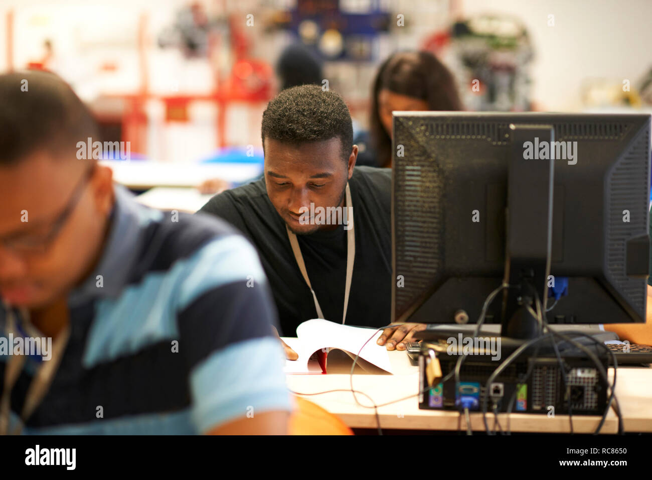 Maschio di istruzione superiore studenti di lavorare alla scrivania in college classroom Foto Stock