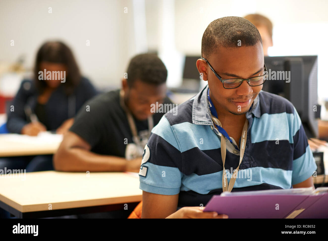 Maschio di istruzione superiore studente la lettura del file in un college classroom Foto Stock