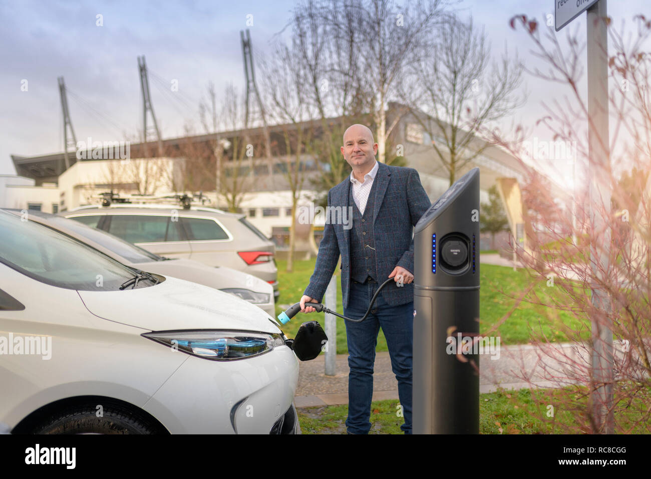 Ritratto di imprenditore nel tamponamento auto elettrica al punto di caricamento, Manchester, Regno Unito Foto Stock