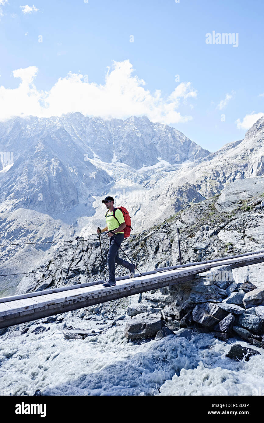 Escursionista attraversando ponte stretto, Mont Cervin, Cervino, Vallese, Svizzera Foto Stock