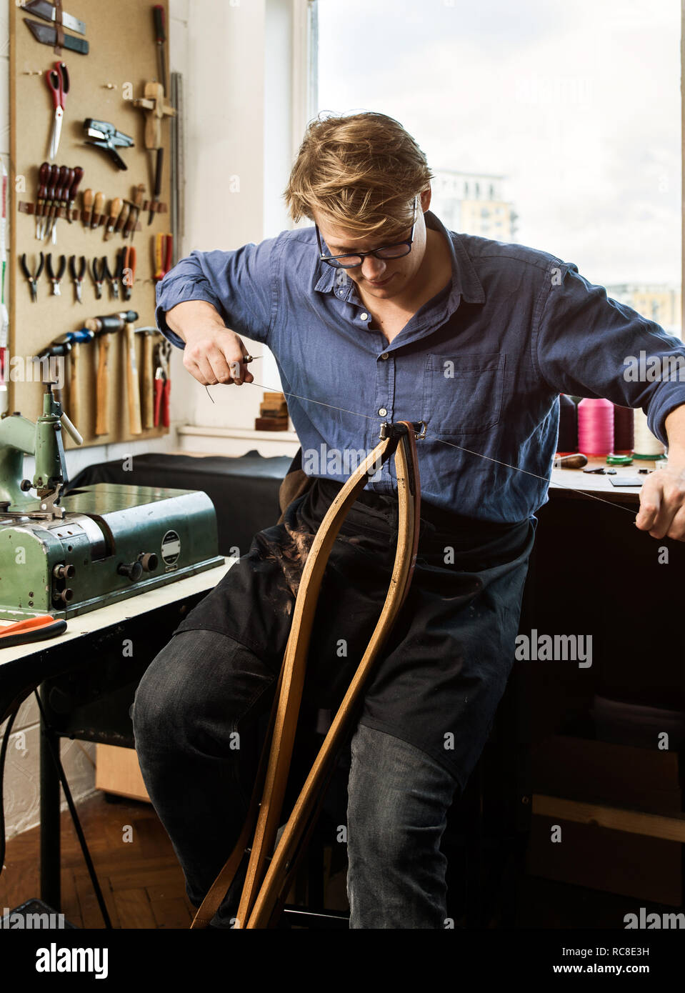 Leatherworker cucitura di borsette in pelle cinghie in officina Foto Stock