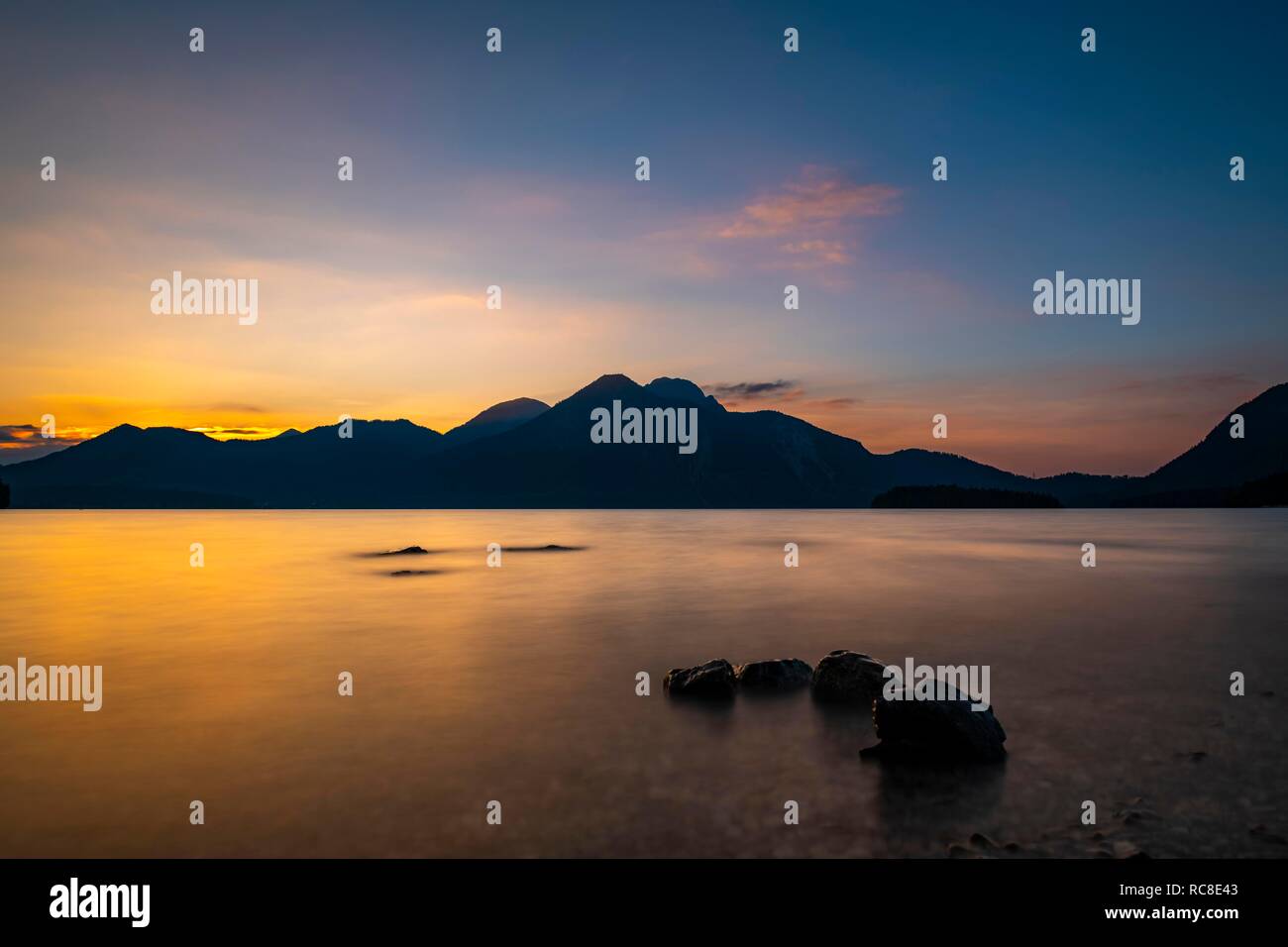 Il Lago Walchensee con pietre in primo piano e Walchensee montagne sullo sfondo al tramonto, Wallgau, Baviera, Germania Foto Stock