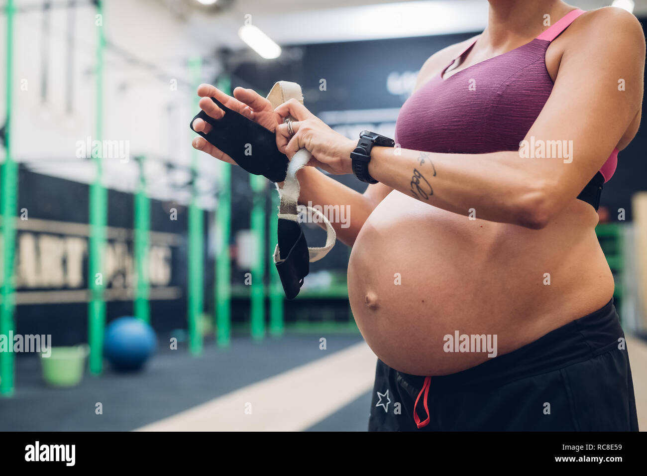 Donna incinta mettendo su guanti allenamento in palestra Foto Stock