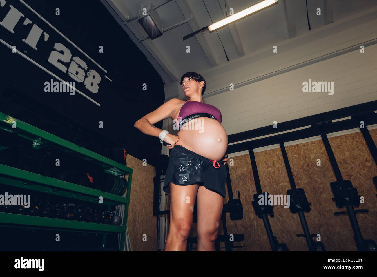 Donna incinta in piedi in palestra Foto Stock