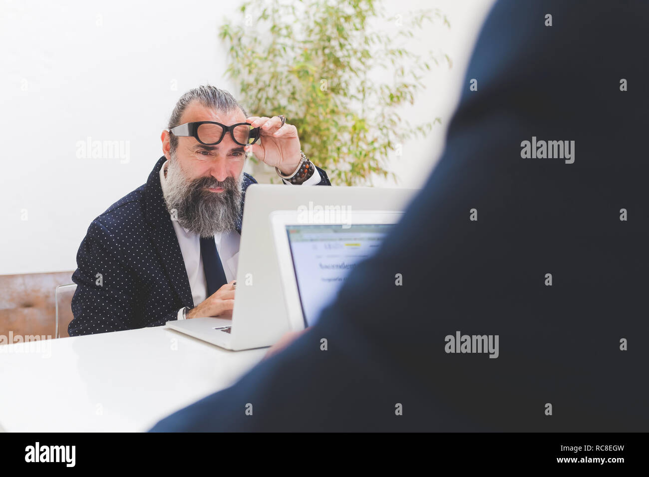 Imprenditore guardando il portatile in ufficio, sulla spalla vista Foto Stock