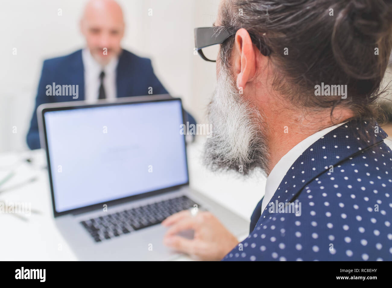 Imprenditore utilizzando il portatile in ufficio, sulla spalla vista Foto Stock