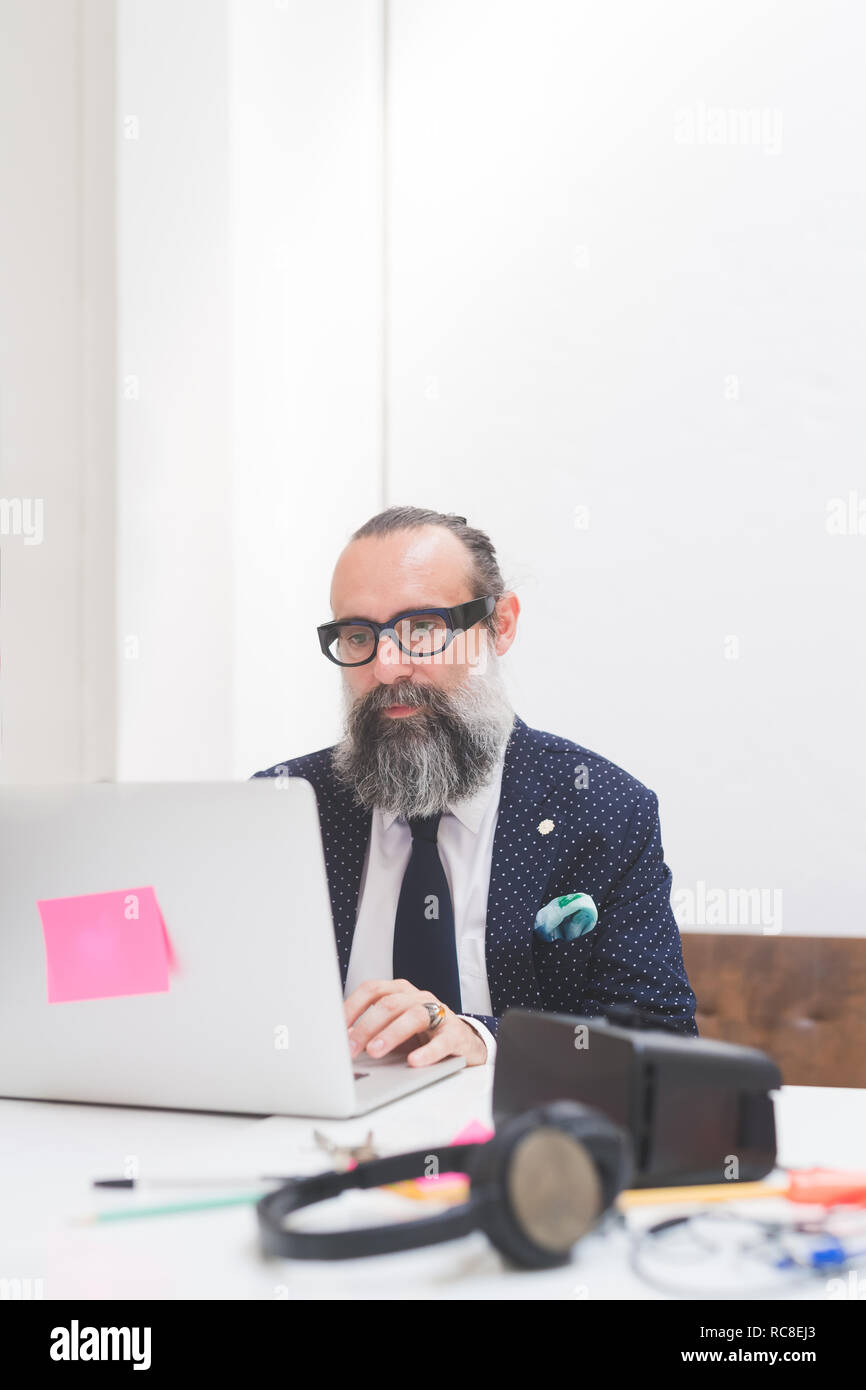 Imprenditore elegante guardando il laptop sulla scrivania in ufficio Foto Stock