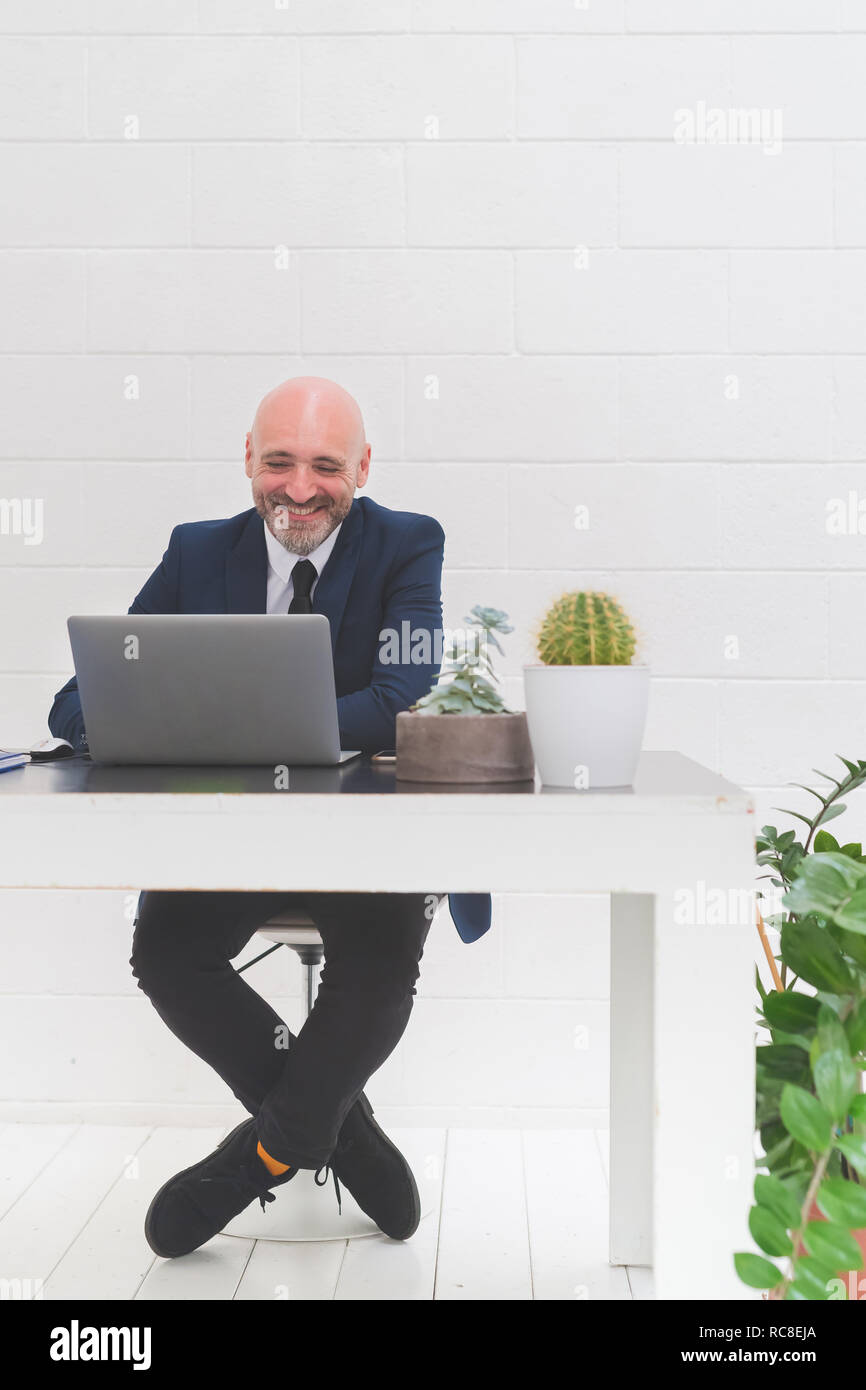 Imprenditore ridere mentre guardando il laptop sulla scrivania in ufficio Foto Stock