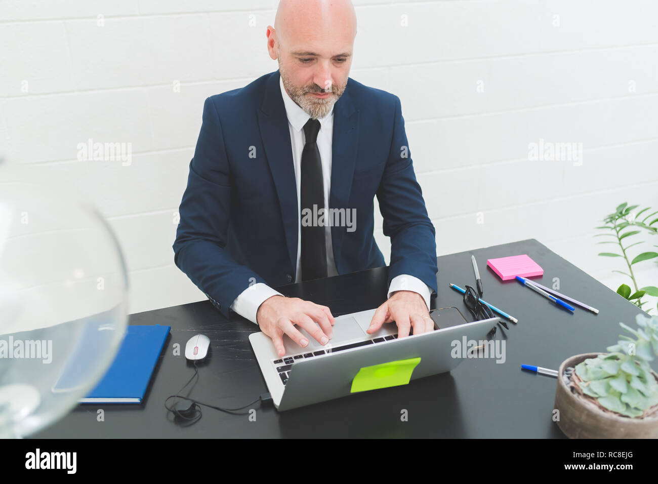 Imprenditore digitando al laptop sulla scrivania in ufficio Foto Stock