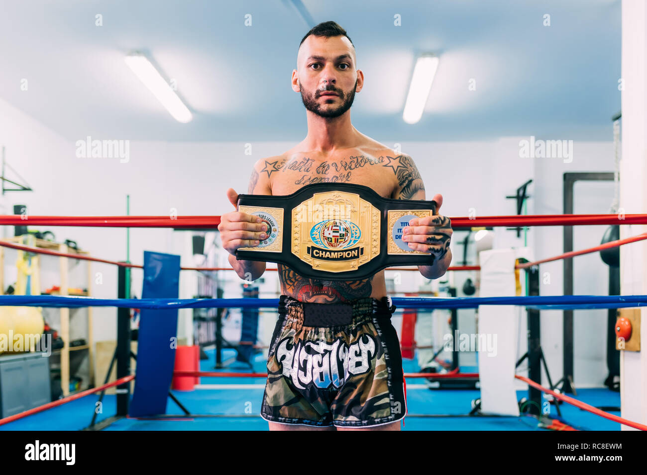 Ritratto del boxer maschio con cinghia di campionato nel pugilato ring Foto Stock