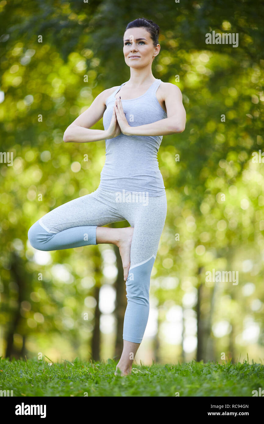 Contenuto lady praticando esercizio di equilibrio all'aperto Foto Stock
