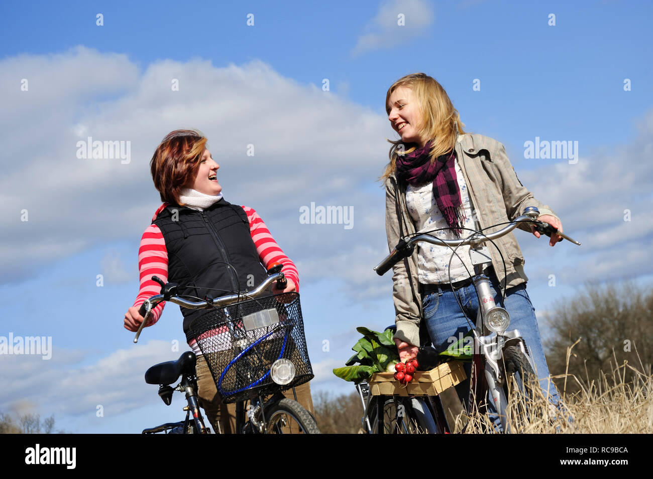 Zwei jungendliche Frauen mit Fahrrad und Gemüsekorb - junges Gemüse | due giovani donne con la loro bicicletta e un cesto di ortaggi Foto Stock