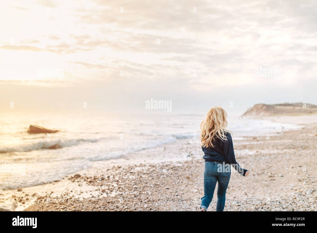 Giovane donna passeggiando lungo la spiaggia, vista posteriore, Menemsha, Martha's Vineyard, Massachusetts, STATI UNITI D'AMERICA Foto Stock