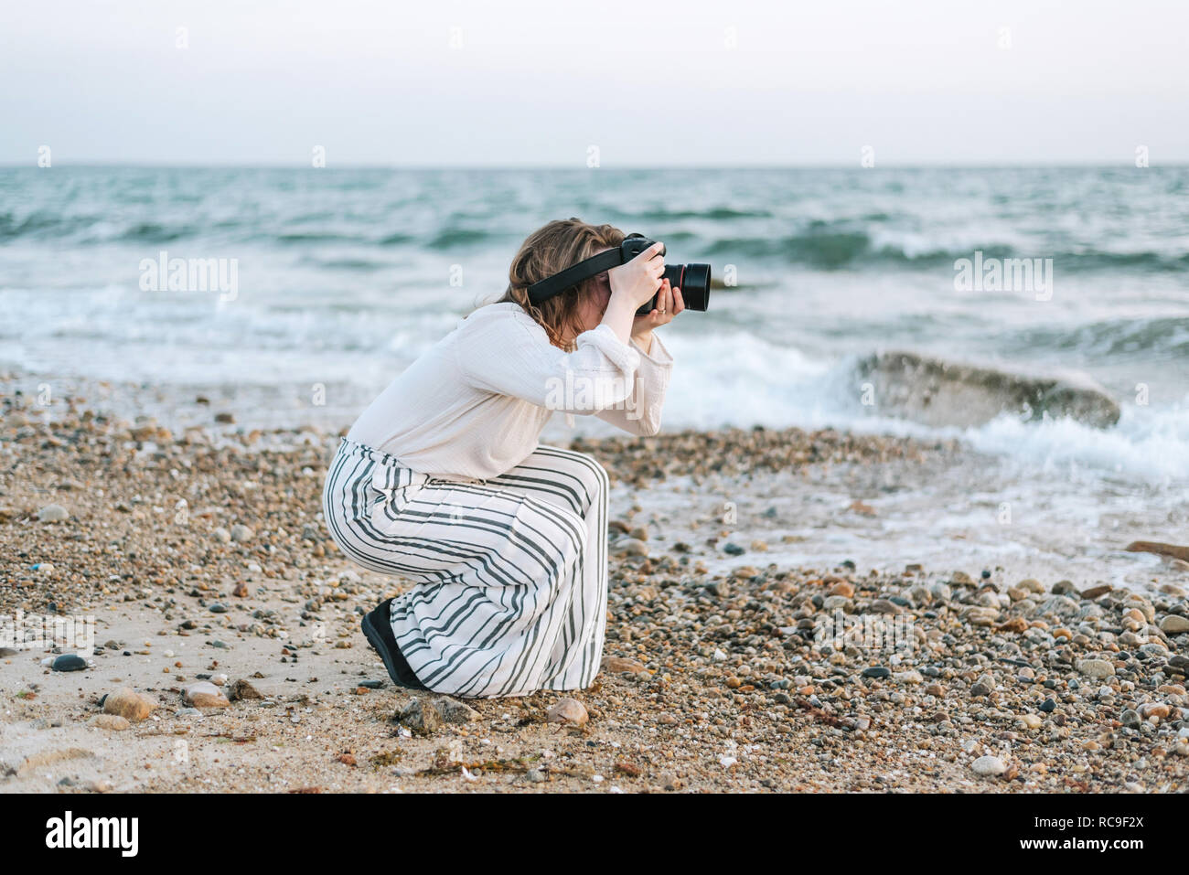 Giovane donna prendendo fotografie da spiaggia, Menemsha, Martha's Vineyard, Massachusetts, STATI UNITI D'AMERICA Foto Stock