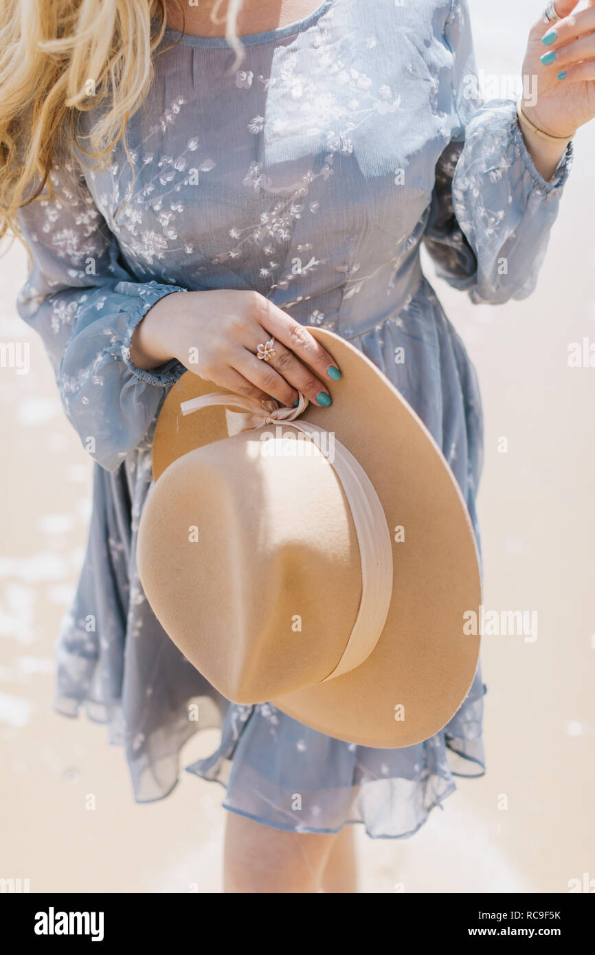 Giovane donna azienda cappello in feltro sulla spiaggia, metà sezione, Menemsha, Martha's Vineyard, Massachusetts, STATI UNITI D'AMERICA Foto Stock