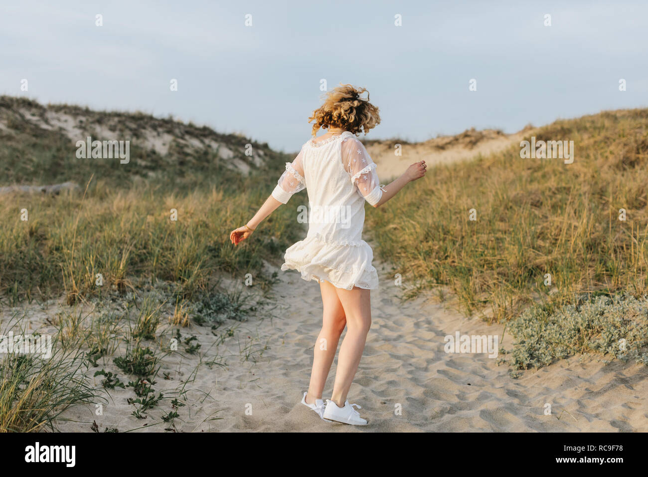 Giovane donna in abito bianco ballare sulle dune costiere, Menemsha, Martha's Vineyard, Massachusetts, STATI UNITI D'AMERICA Foto Stock