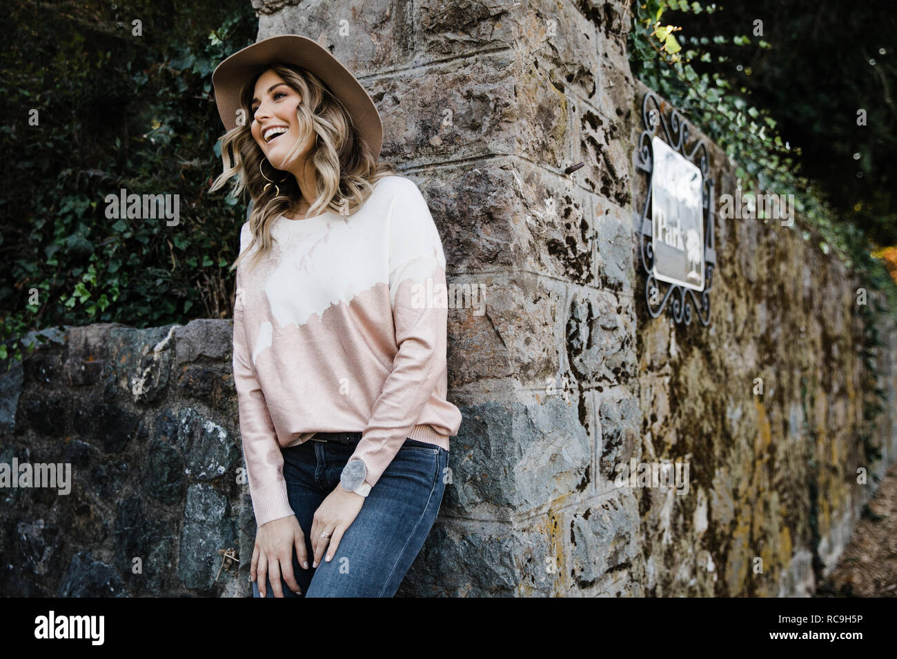 Donna appoggiata sul vecchio muro di pietra nel parco, San Rafael, California, US Foto Stock