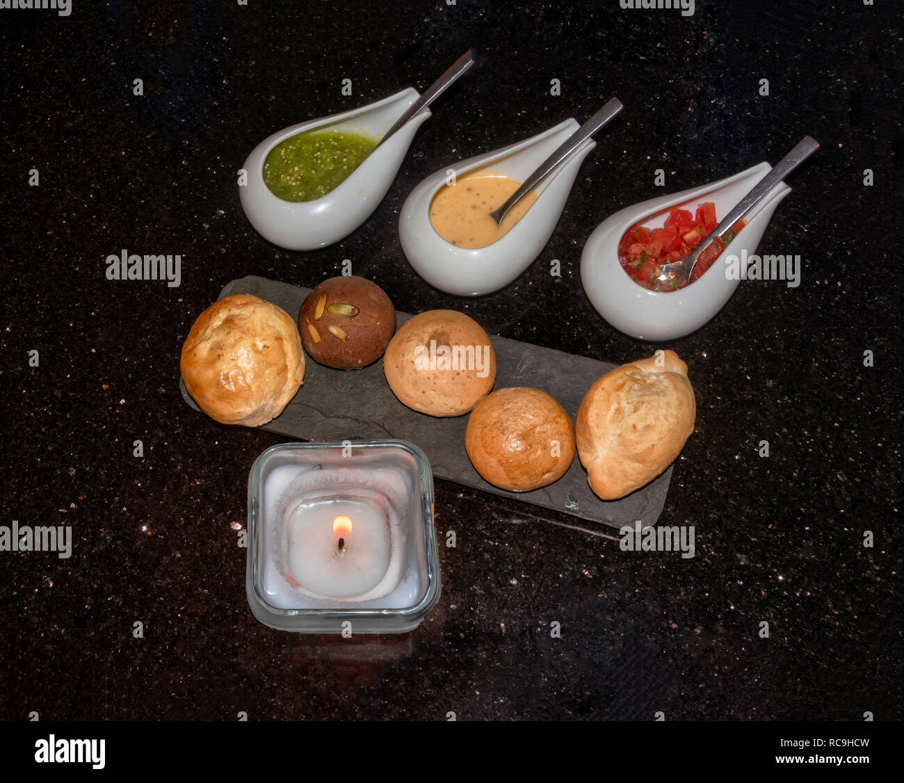 Molti tipi di pane e salse, con candela in elegante granito nero del tavolo Foto Stock