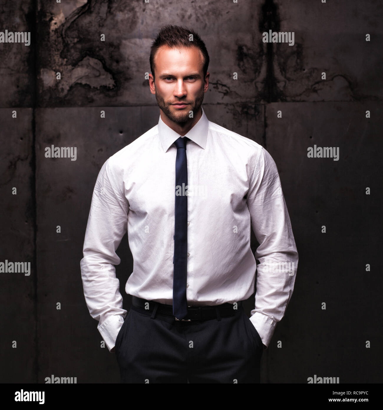 Uomo bello indossare una camicia bianca su sfondo grunge. Foto Stock