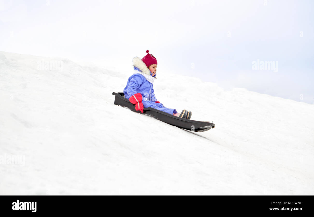 Felice bambina lo scorrimento verso il basso sulla slitta in inverno Foto Stock