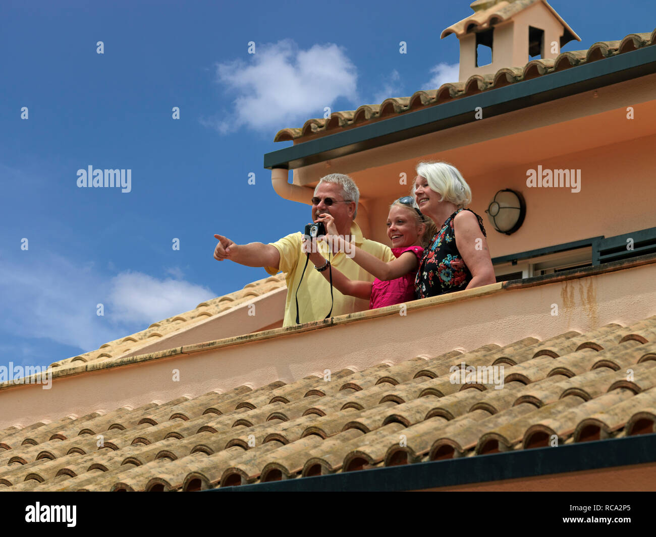 Älteres Ehepaar mit Enkeltochter auf dem Balkon ihres Ferienhauses | coppia di anziani sul balcone del loro appartamento di vacanza Foto Stock