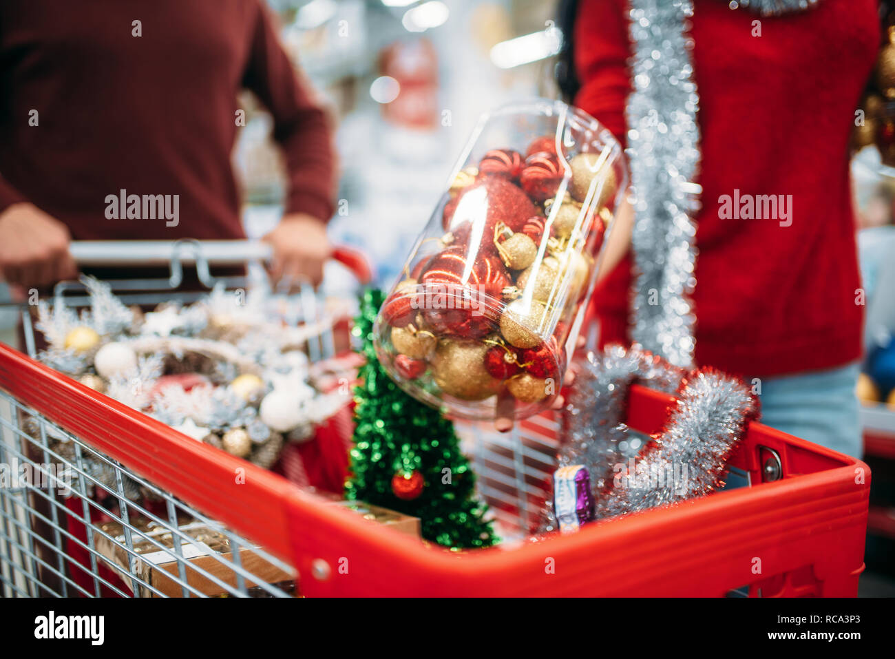 Coppia giovane mettere nel carrello decorazioni di Natale, gli acquisti in un supermercato, la tradizione di famiglia. Dicembre di shopping di merci per le vacanze Foto Stock