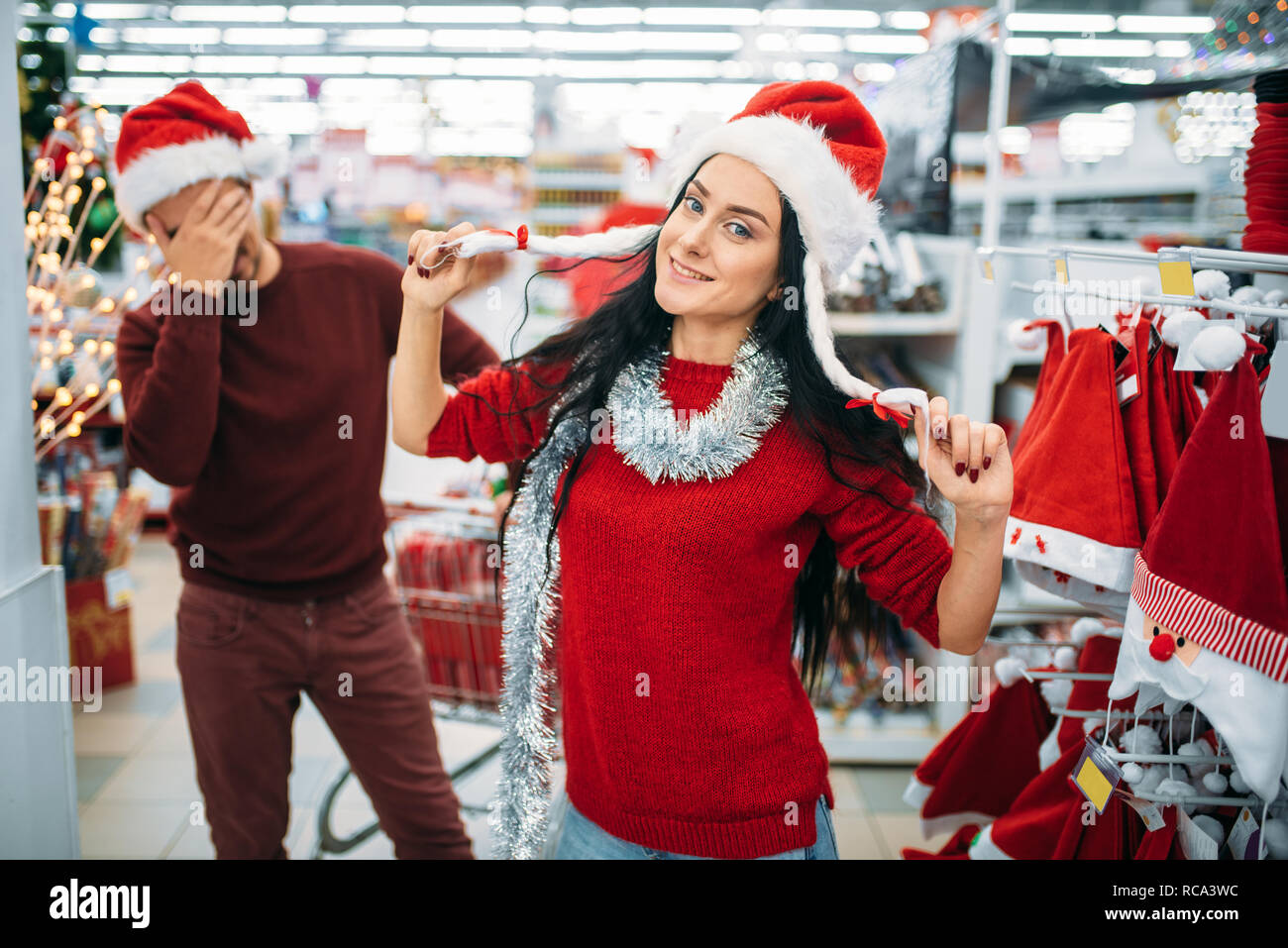 Divertente coppia giovane cercando sui vestiti di natale nel supermercato,  la tradizione di famiglia. Dicembre shopping vacanze di merci e decorazioni  Foto stock - Alamy