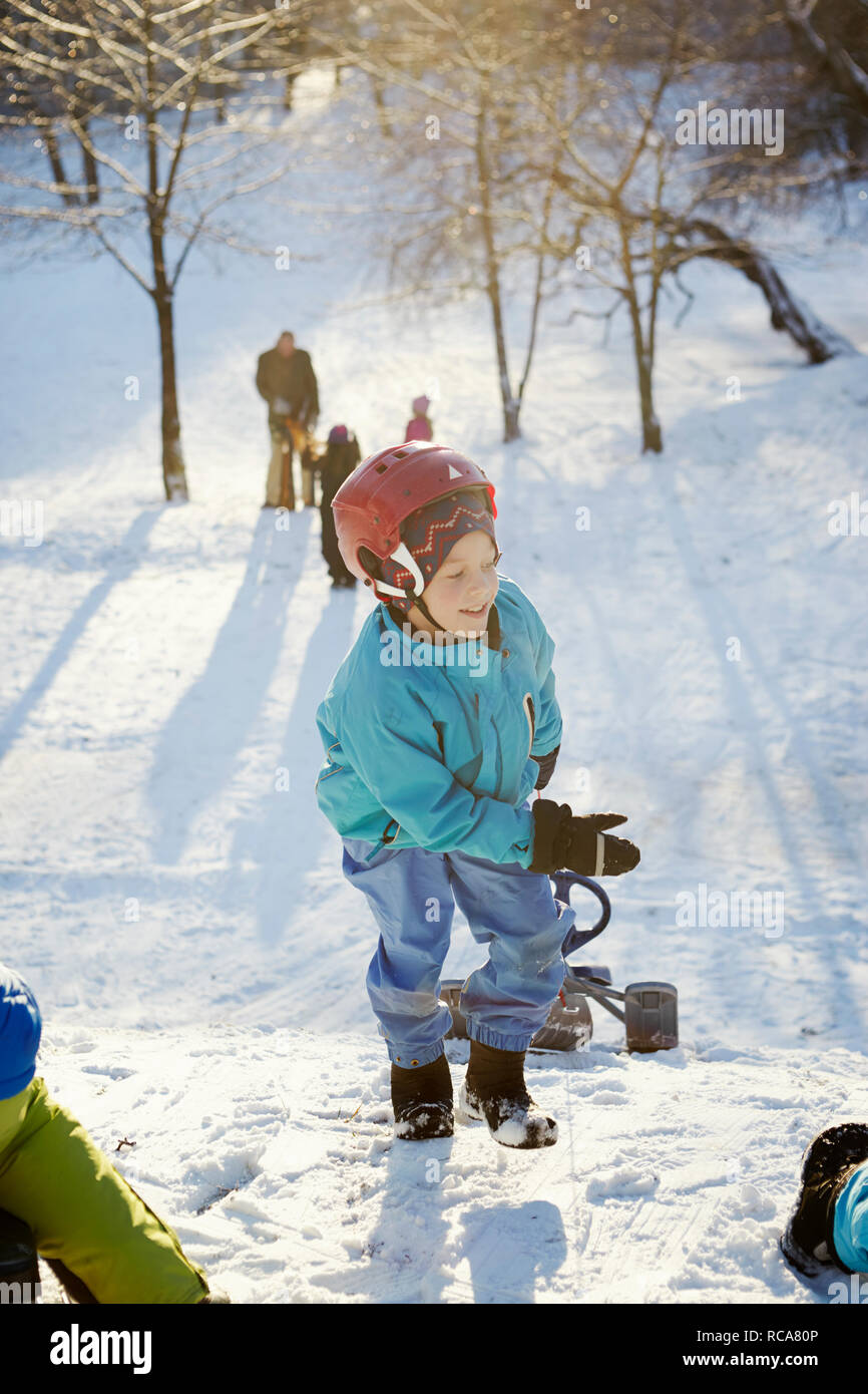 Ragazzo tirando scooter neve in salita Foto Stock